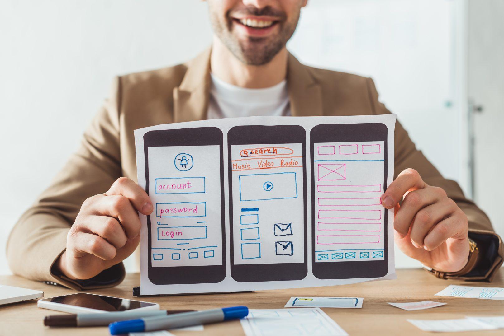 A man holding a piece of paper featuring mobile web design
