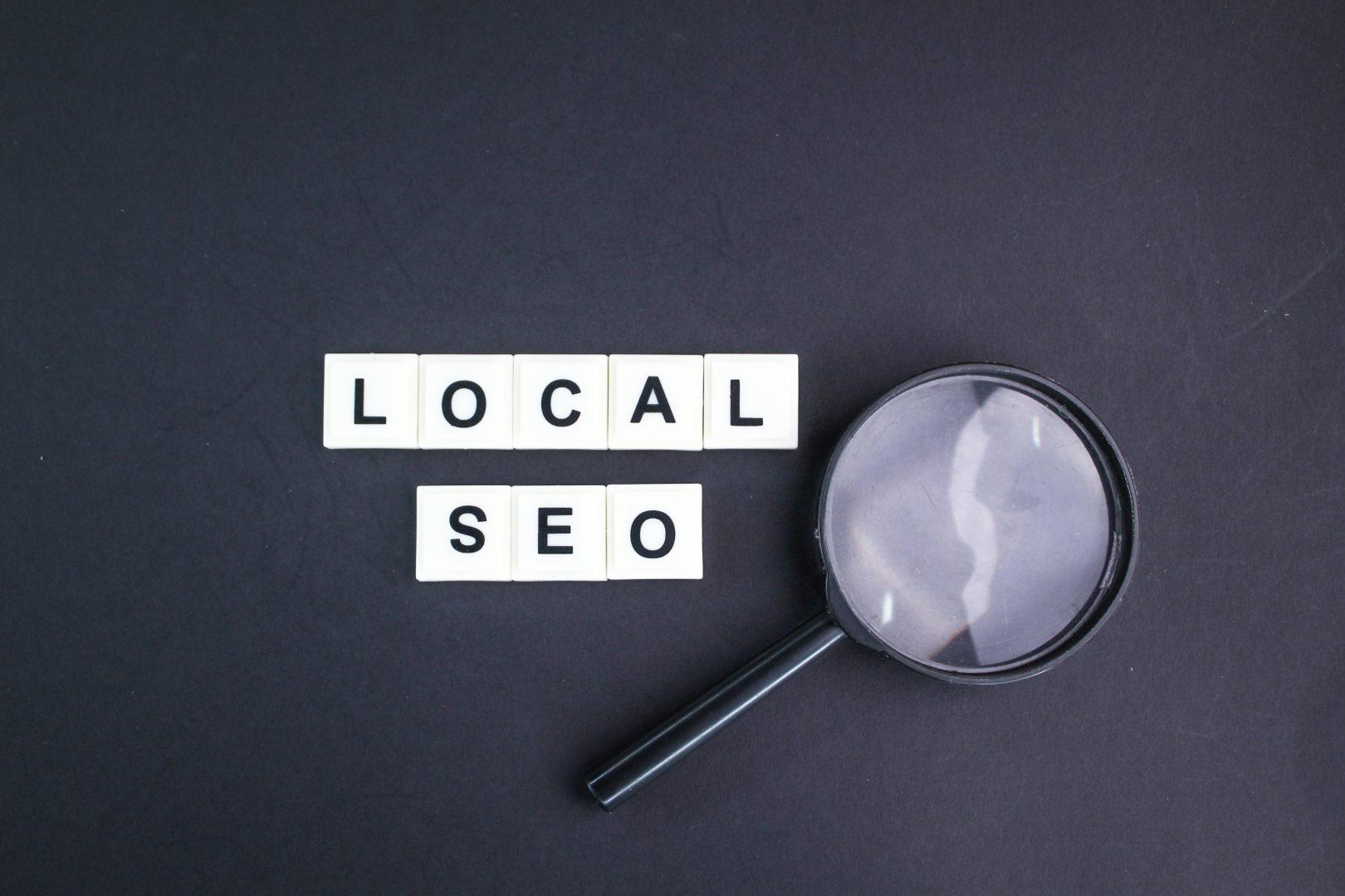 Scrabble tiles spelling out local SEO next to a magnifying glass | Local SEO Surrey