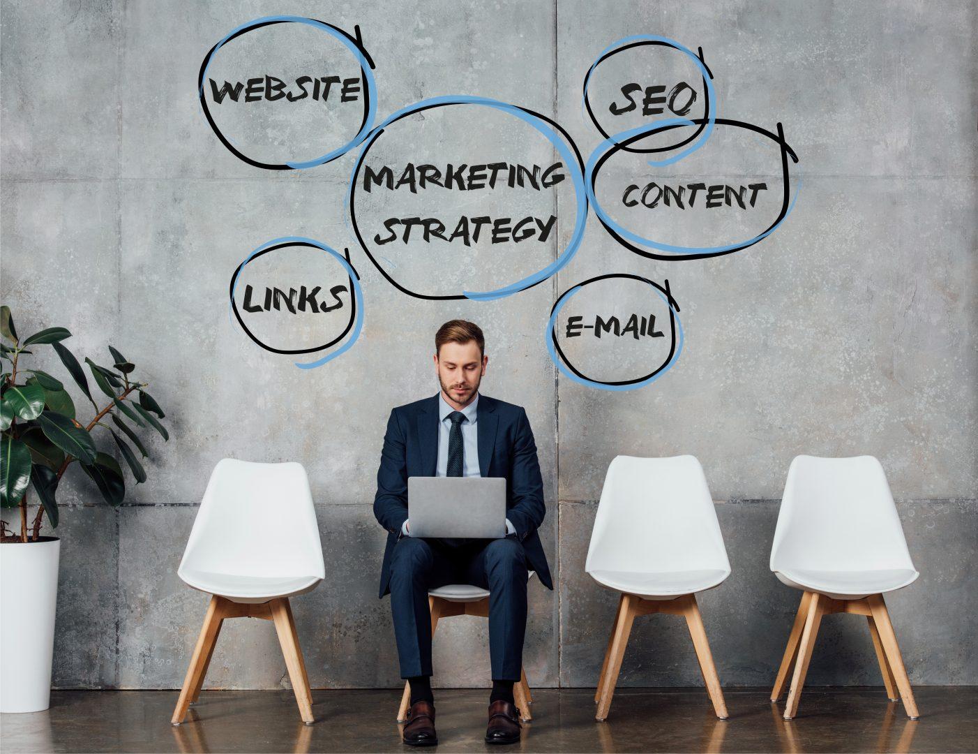 smiling businessman sitting on chair and using laptop