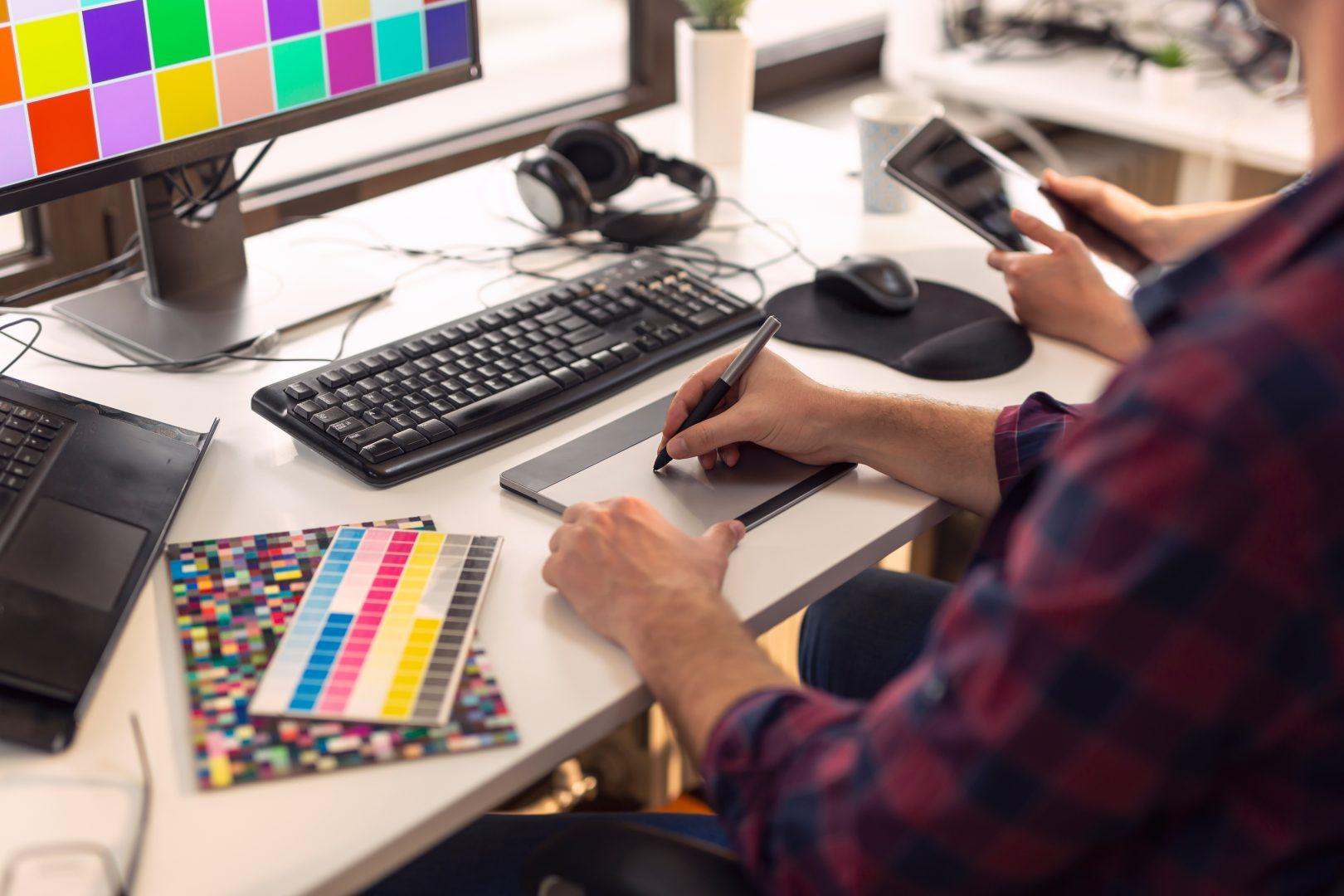A graphic designer using a drawing tool at their desk