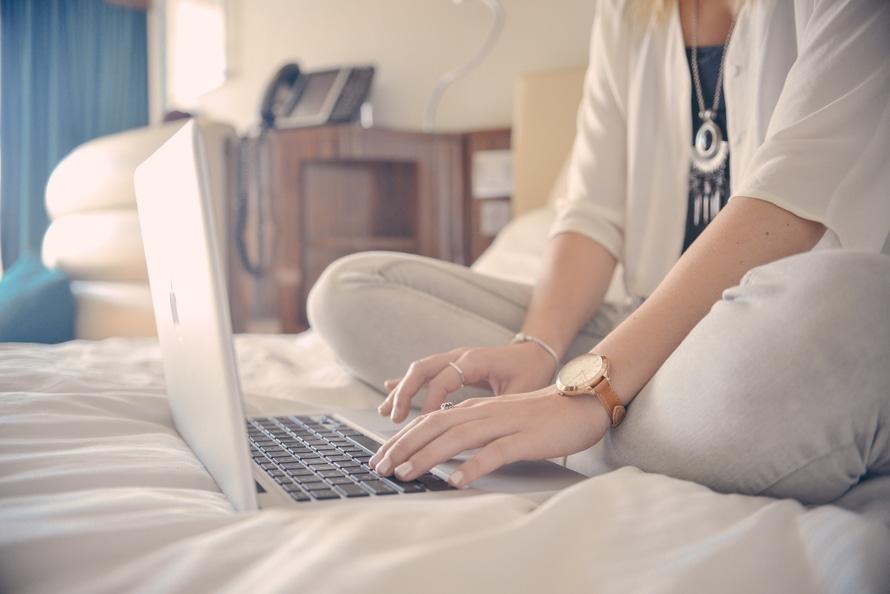 Woman typing on a laptop while sitting on a bed | Marketing Farnham | Thunderbolt Digital