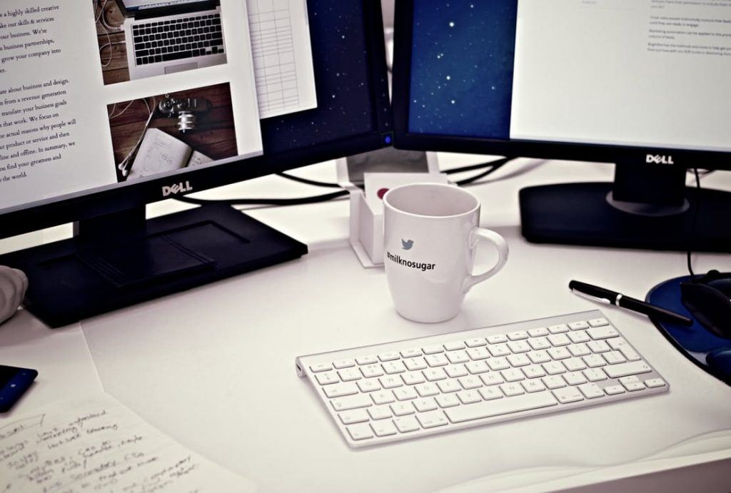 An office desktop with two computer screens, a keyboard & mug | Thunderbolt Digital